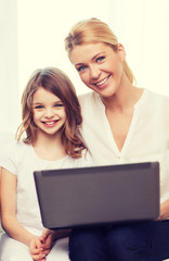 smiling mother and little girl with laptop at home