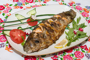 Fried fish on a plate with vegetables