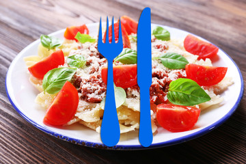 Pasta bolognese with cherry tomatoes in white plate on wooden table, closeup