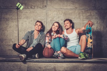 Cheerful friends with with skateboard taking selfie outdoors