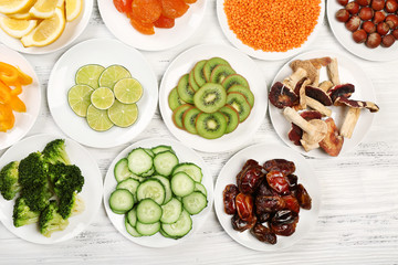 Different products on saucers on wooden table, top view