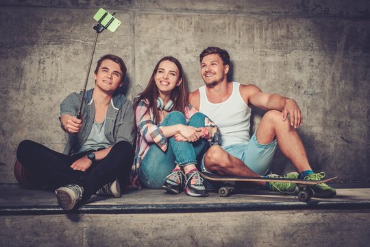 Cheerful friends with with skateboard taking selfie outdoors