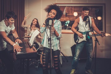 Obraz premium Multiracial music band performing in a recording studio