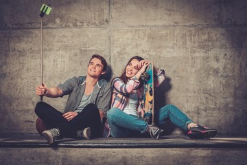 Young couple with skateboard  taking selfie outdoors