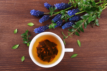 Cup of herbal tea with flowers on wooden table, top view