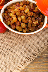 Raisins in bowl with grapes on table close up