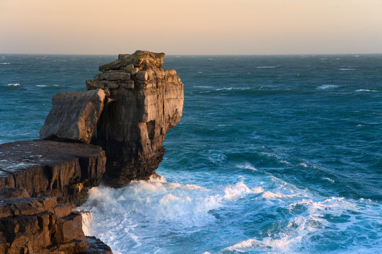 Waves crashing over the rocks at Pulpit Rock near Portland Bill in Dorset, England.