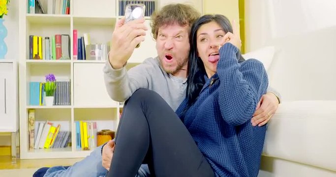 Happy couple having fun taking selfie pictures at home 4K