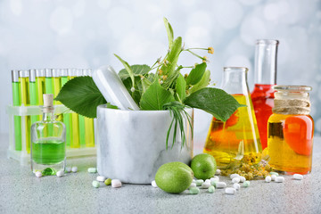 Herbs in mortar, test tubes and pills,  on table, on light background