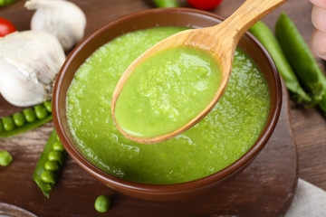Tasty peas soup and vegetables on table close up