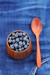 Fresh wild blueberries in wooden vase with wooden spoon on fraye