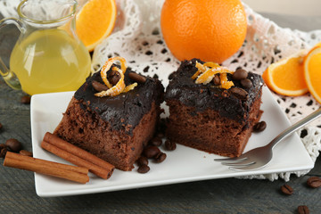 Portion of Cake with Chocolate Glaze and orange on plate, on wooden background