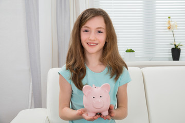Obraz na płótnie Canvas Girl Holding Piggy Bank