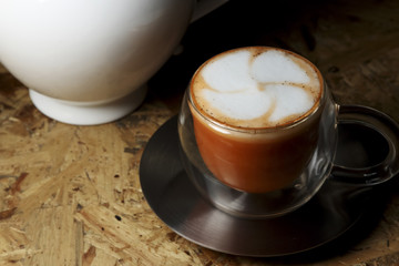 Hot Thai tea latte decorated with white pot on wooden background, latte art.