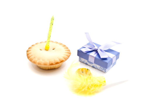 cupcake with yellow birthday candle, gift and whistle