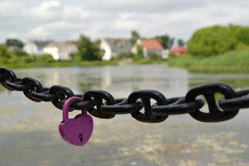 Naklejka premium The lilac lock hangs on a chain against the river. Kaliningrad region