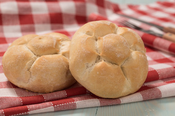 Fresh bread on a wooden board with a red and withe checkered tablecloth