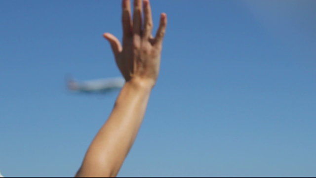Woman looking at landing airplane, waving hand to welcome new tourists arrival