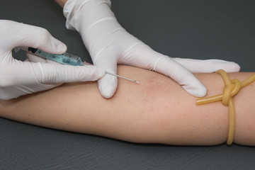 woman arm with a tourniquet getting injection with a syringe at