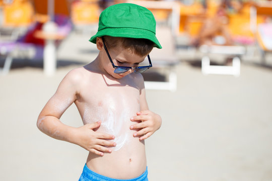 Little Boy In Sunglasses Applying Sunscreen