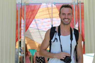 Portrait of a handsome young man with a camera against colorful background 
