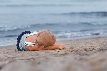 Little pretty kid in bathing suit lying on beach