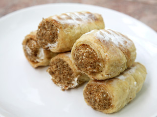 Sweet homemade tube with cream and nuts on white plate