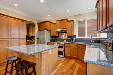 Classic kitchen with island and stainless steel fridge.