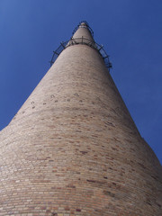 Schornstein/ein hoher Schornstein vor einem wolkenlosen blauem Himmel, Ziegelbau, Blick aus der...