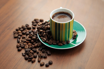 Mug of strong coffee on scattered coffee beans