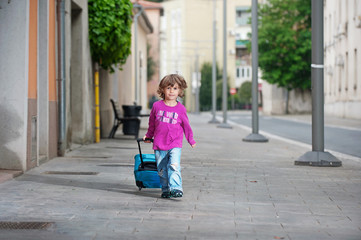 Cutle little boy with a luggage bag on the street