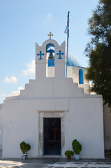 Pretty greek stone church with blue dome and walls whitewashed