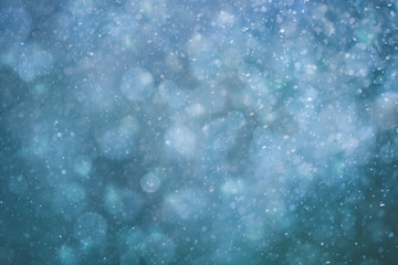 Abstract blurred turquoise blue color snowfall or rainfall bokeh background. Beautiful freshness snowy New Year and Christmas background.