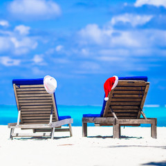 Christmas concept: beach loungers with red Santa and straw hats