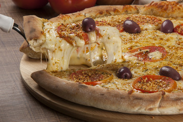 Tasty pizza, tomatoes and others ingredients on a wooden backgro
