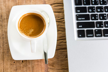Coffee cup and laptop in coffee shop