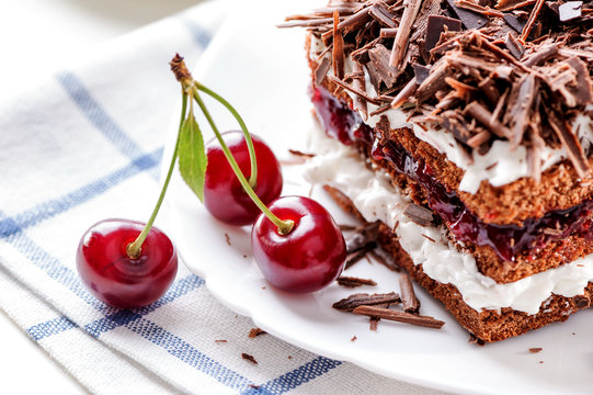 Black Forest cake piece on white plate with cherries berries close-up 
