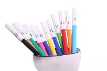 Couple of colorful sketch pen are kept over beautiful bowl and photographed against white background
