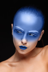 Portrait of a woman who is posing covered with blue paint