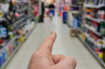 Zeigefinger deutet in Richtung der gesuchten Regale im Supermarkt