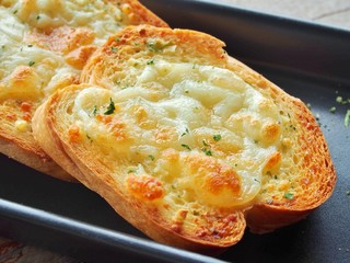 Close-up of a dish of garlic bread with cheese.‏