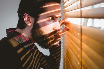 Fototapeta na wymiar Hipster businessman peeking through blinds