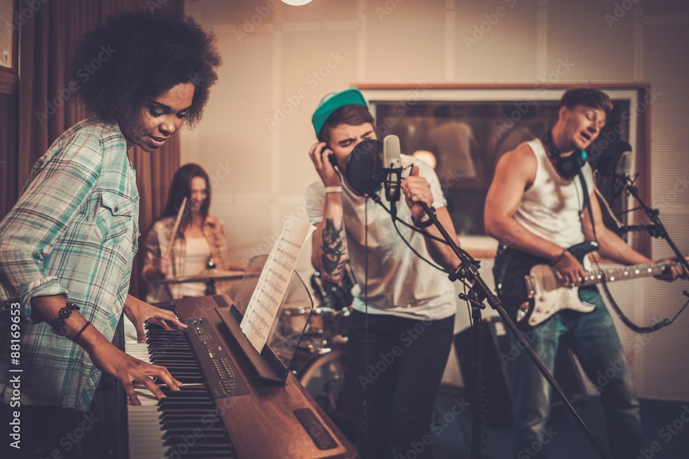 Wall mural Multiracial music band performing in a recording studio