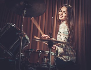 Fototapeta na wymiar Young cheerful girl behind drums on a rehearsal