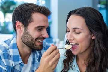 Young happy couple feeding each other with cake 