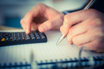 Businessman using a calculator and writing