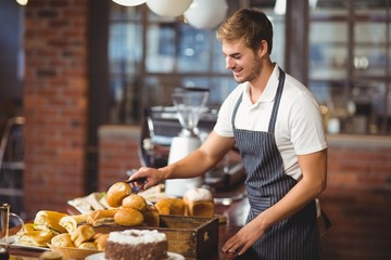 Handsome waiter picking up a roll