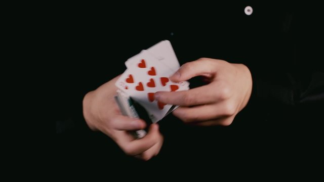 Hands in darkness shuffled deck of cards