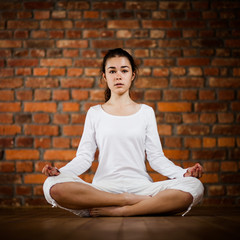 Woman exercising yoga against brick wall 