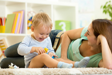 happy child holds animal toy playing with mom in nursery